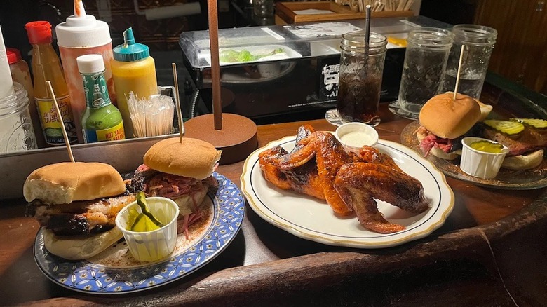 Three different plates of barbecue sitting atop a wooden bar at Tonk's Barbecue in Chicago