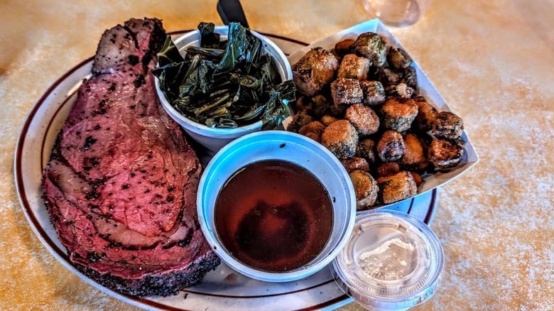 Prime rib with collard greens on a ceramic plate.