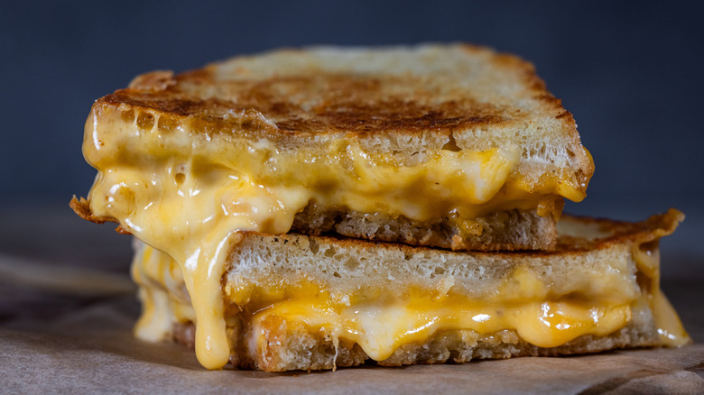 Two halves of a melty grilled cheese sandwich stacked one on top of the other.