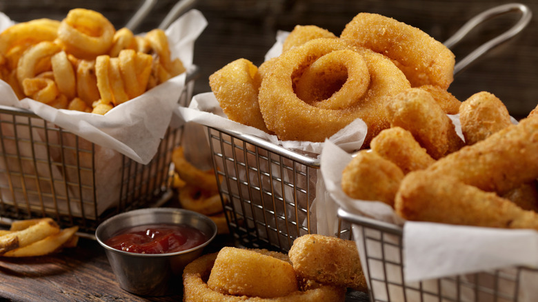 baskets of curly fries, fried onion rings, and mozzarella sticks
