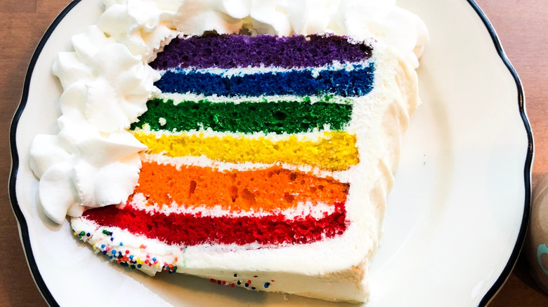 a slice of rainbow cake from goddess and the baker