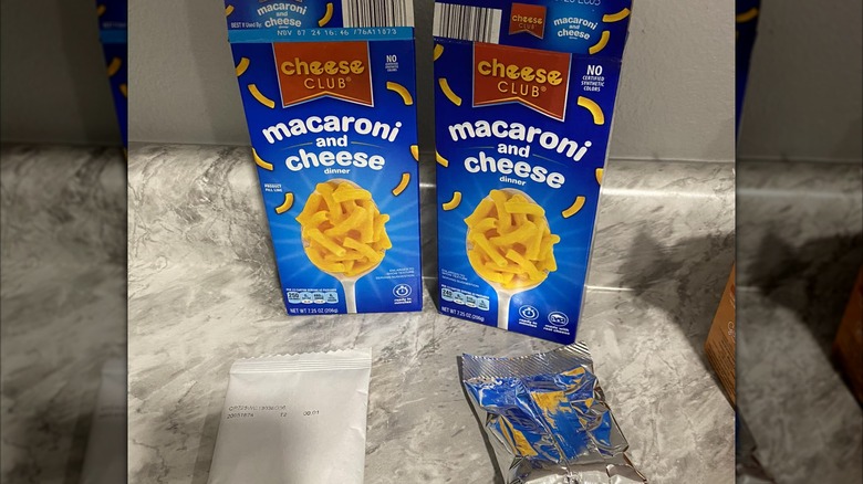 Two boxes of Aldi's Cheese Club mac and cheese on a marble countertop