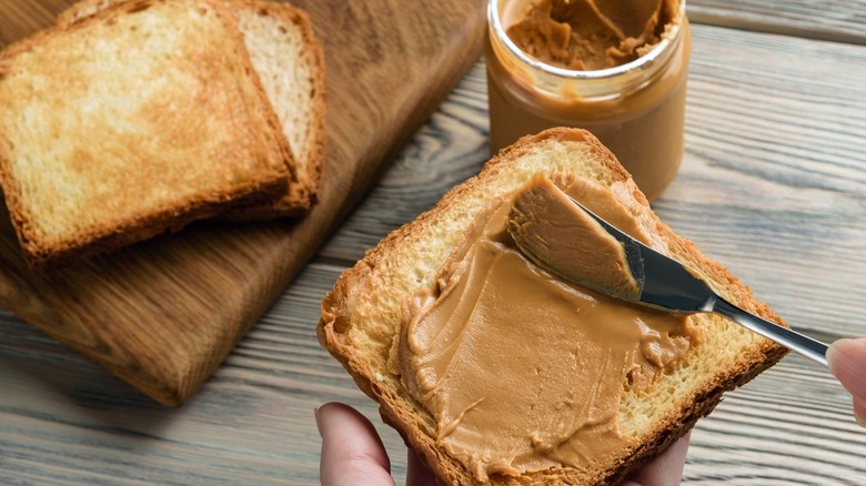 peanut butter spread on toast with an open jar