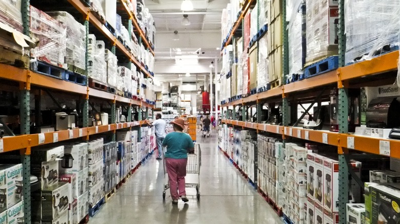 A person with a shopping cart browsing the aisles of Costco