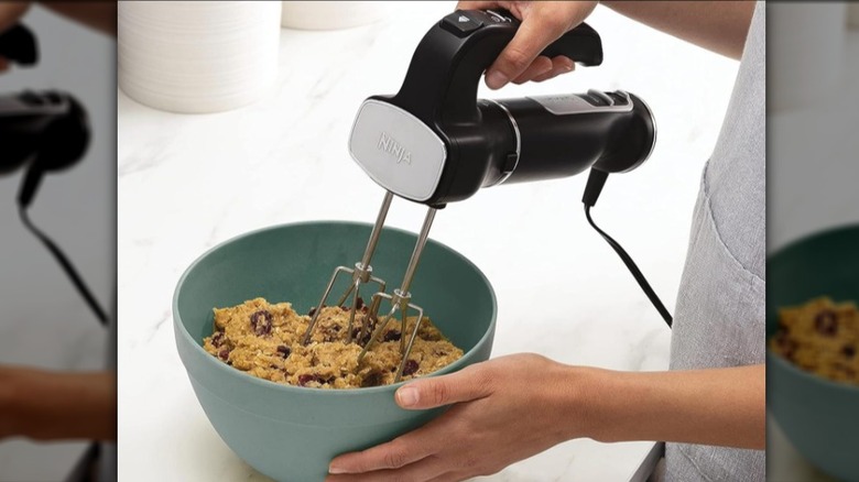 Person using the Ninja hand mixer to mix dough in a teal bowl