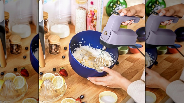 Hand using the lavendar 6-speed hand mixer in a blue bowl with batter