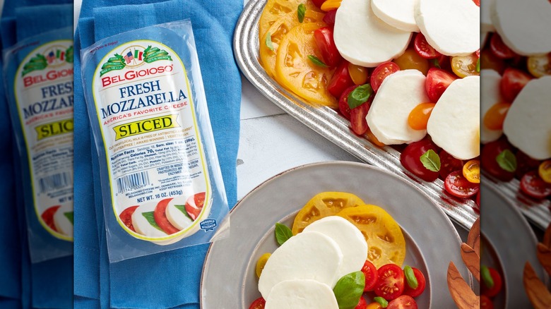 A package of BelGioioso sliced mozzarella next to a caprese salad on a plate