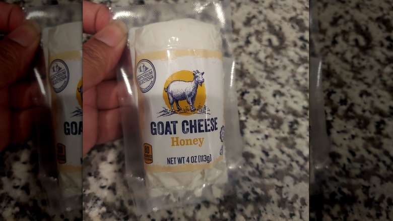 A person holding a log of honey goat cheese