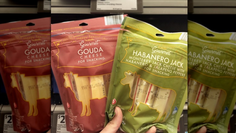 A person holding two packages of gourmet snacking cheese sticks