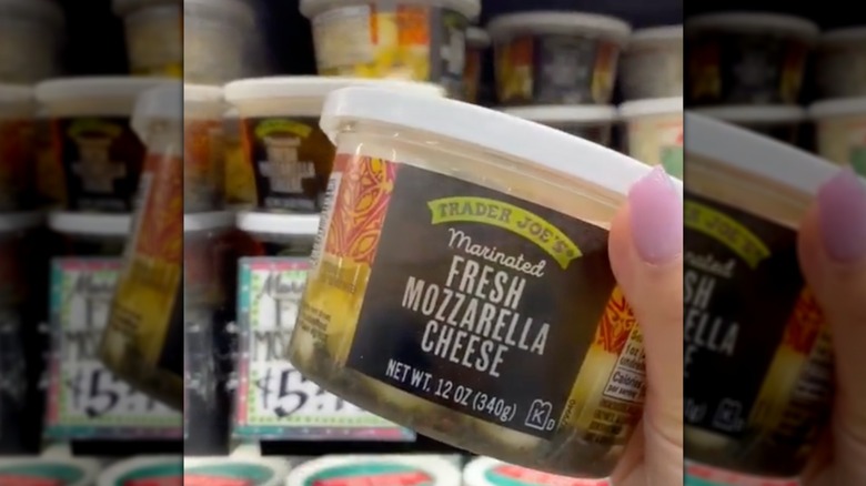 A woman holding a Trader Joe's marinated fresh mozzarella cheese container