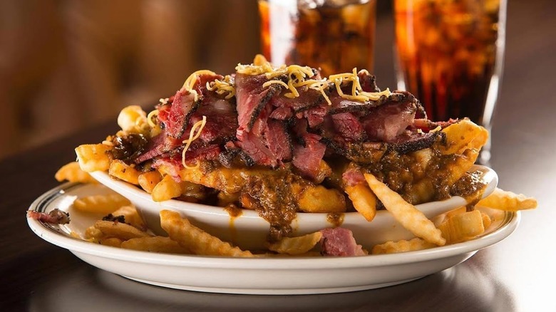 A large plate of french fries topped with pastrami and cheese