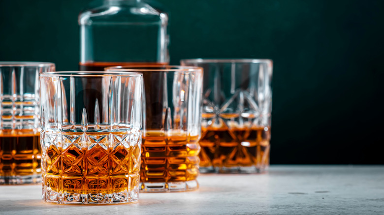 A whiskey decanter next to filled glasses of whiskey