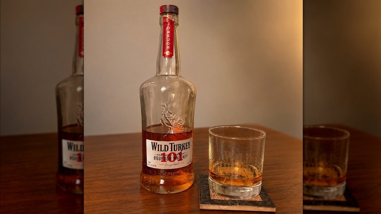 A bottle of Wild Turkey 101 Bourbon next to a full glass