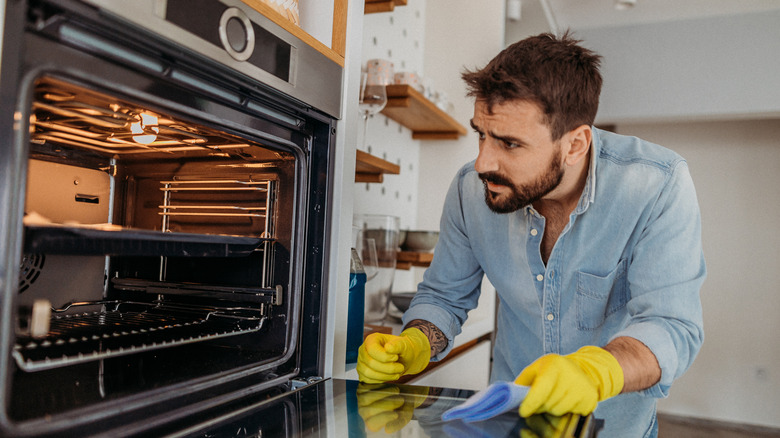 man cleaning oven