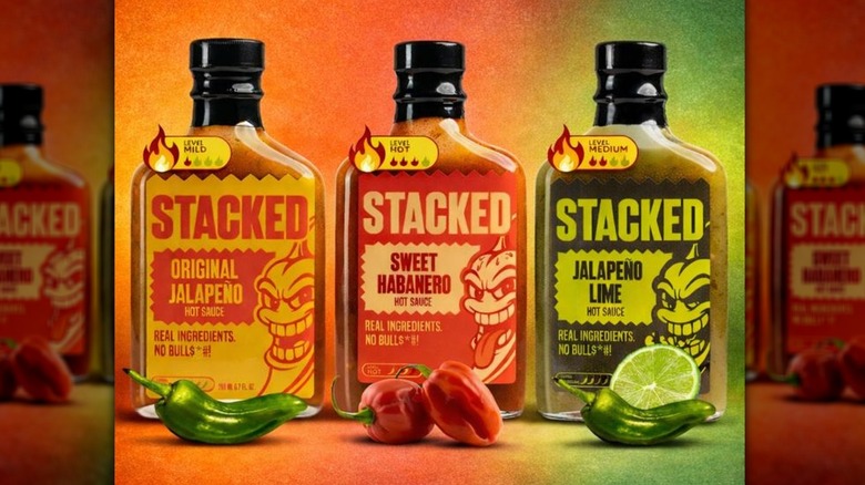 Three bottles of Stacked hot sauce on a red and green background