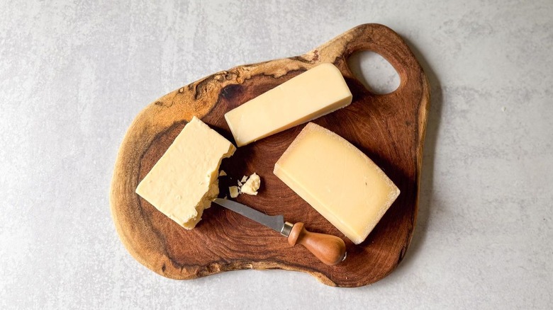 cutting board with cheese wedges and knife