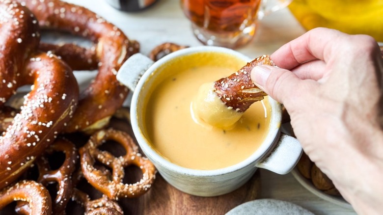 dipping a soft pretzel into beer cheese dip