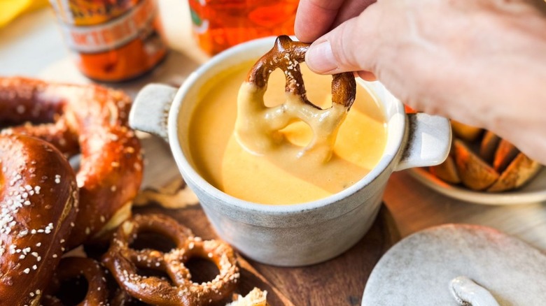 Dipping a pretzel into the best beer cheese pretzel dip
