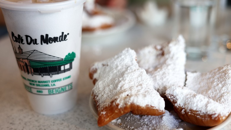 Styrofoam cup with Cafe Du Monde logo and plate with 6 powder-sugar dusted beignets