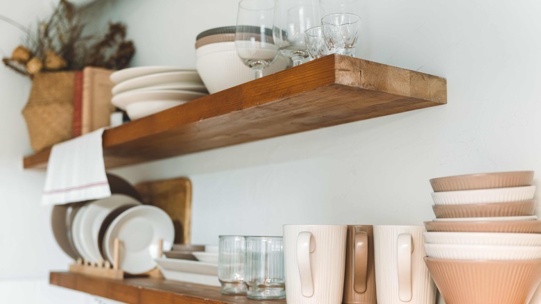 Floating shelves hold dishes and other items in a kitchen.