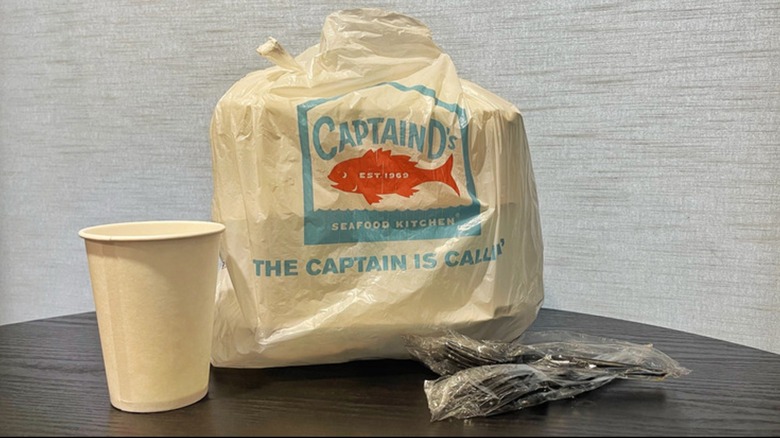 Captain D's takeout bag with paper cup and plastic utensils