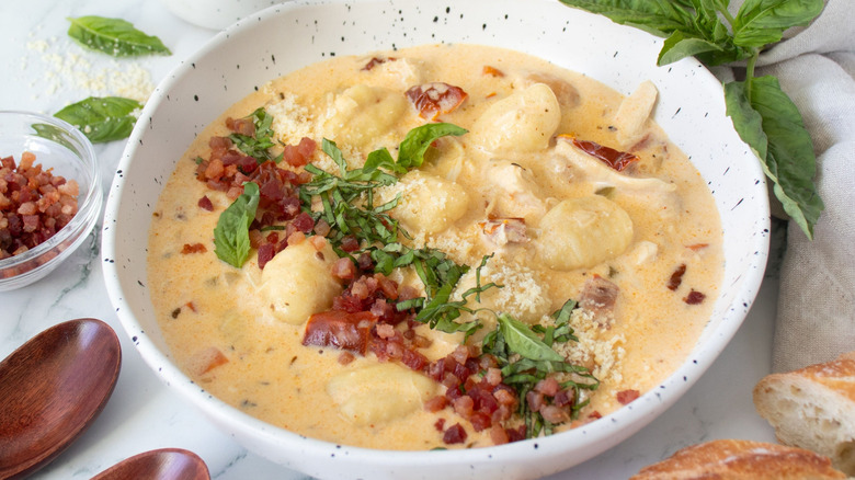 Bowl of chicken gnocchi soup topped with basil and pancetta