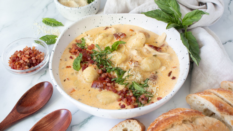 Bowl of chicken gnocchi soup topped with basil and pancetta