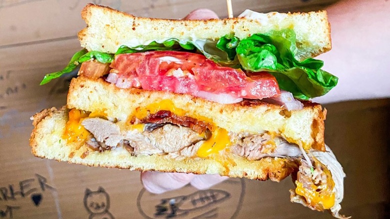 A person holding the Mike's Famous Duck Club sandwich at The Tattooed Moose