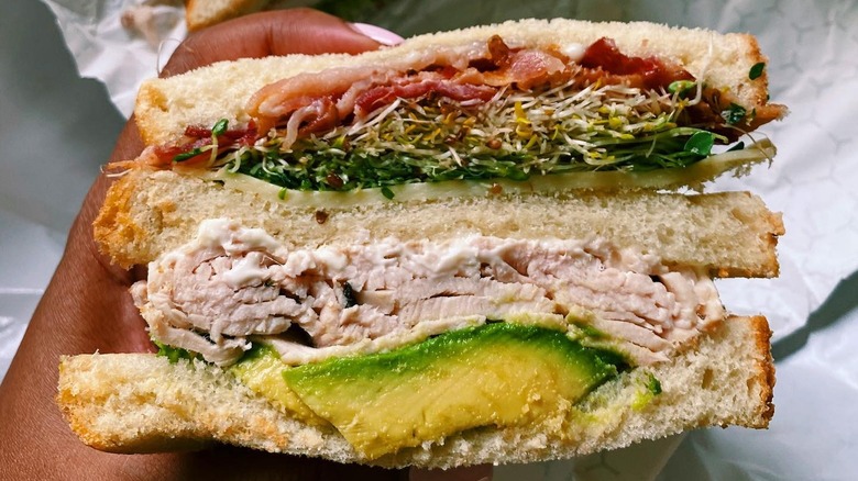 A person holding a turkey club sandwich from Stachowski's Market
