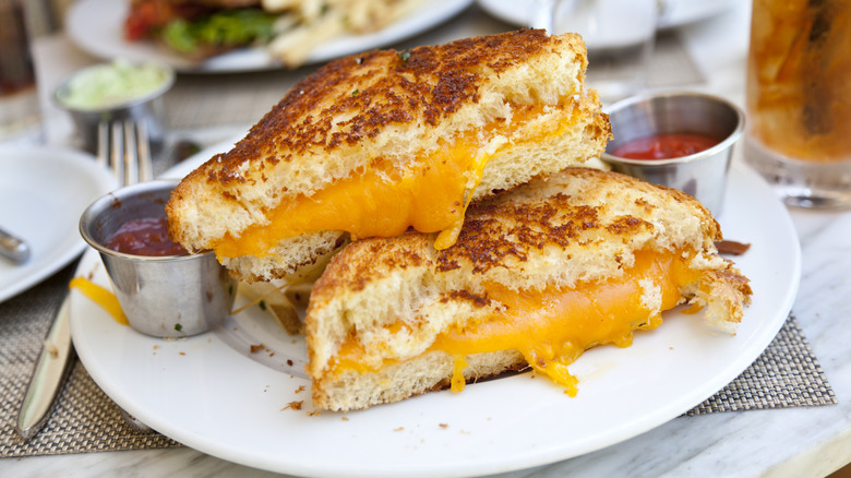 Grilled cheese sliced in half with two pots of ketchup