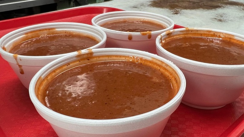 Four Styrofoam bowls of chili on red plastic tray