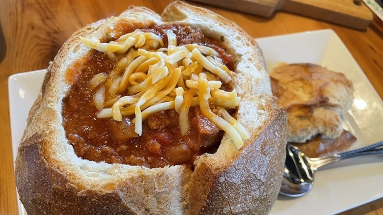 Chili with cheese in bread bowl on white plate