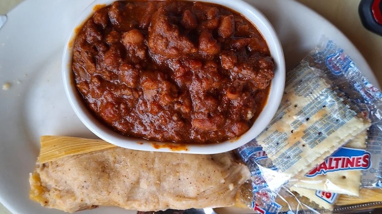 Tamales on plate with bowl of chili and saltine crackers