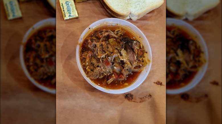 Close-up of a bowl of Everything Chili with white bread and butter packets in the background