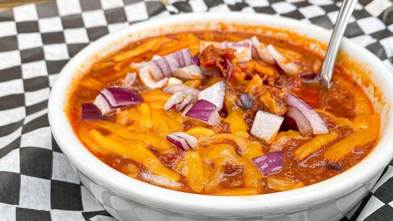Brisket chili with cheese and onions on black and white check paper
