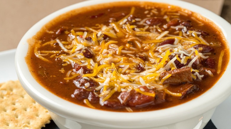 Bowl of brisket chili with cheese and crackers on the side