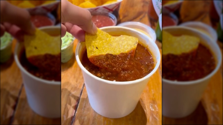 Tortilla chip being dipped into a styrofoam cup of chili