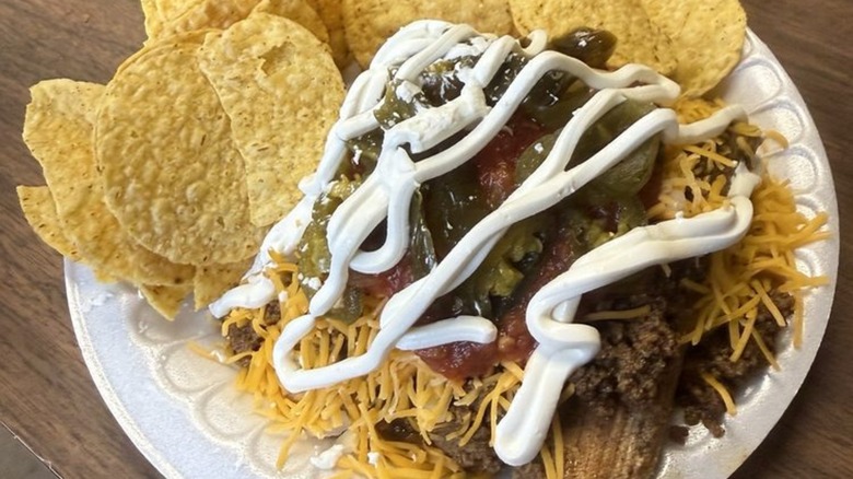 Chili and sour cream over tamales with tortilla chips