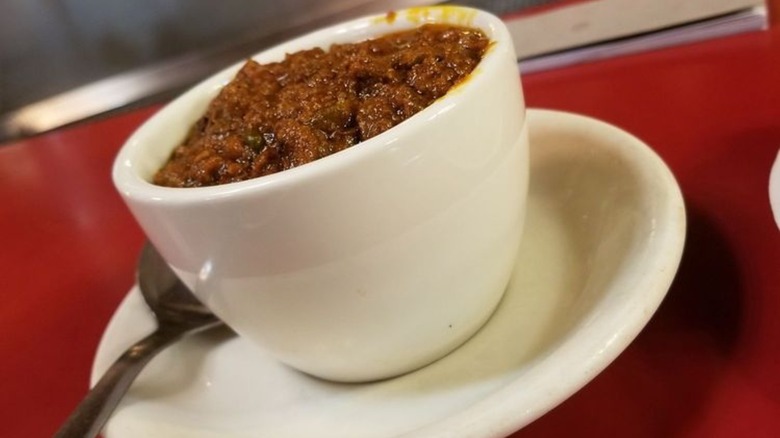 Bowl of chili with spoon on red table