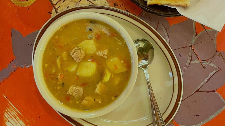 Bowl of green chili on plate with spoon and colorful table