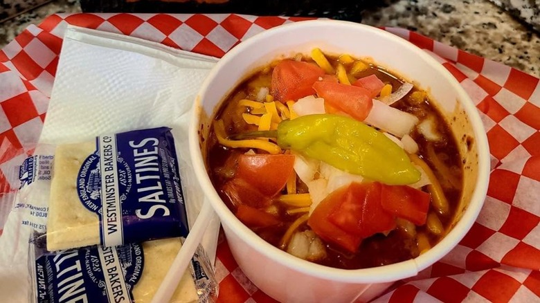 Bowl of chili with cheese, onions, tomatoes, and banana pepper with crackers