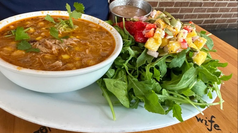 Bowl of chicken chili with cilantro on plate with salad
