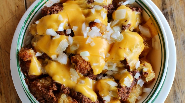 Chili, cheese, and onions in bowl on wooden background