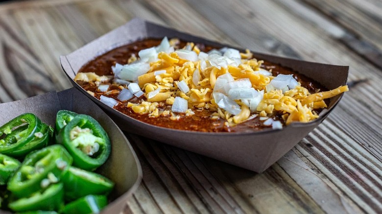 Tray with chili, cheese, and onions and another tray of jalapeños