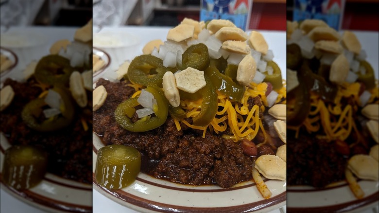 Bowl of chili with jalapeños, cheese, onions, and oyster crackers