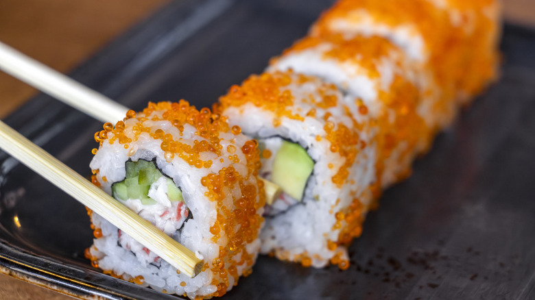 up close on a roll of sushi with chopsticks