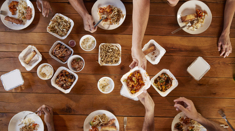 People sharing several dishes out of takeout containers