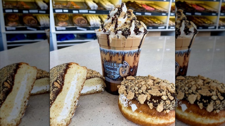Filled donuts on a countertop with an elaborate coffee drink between them