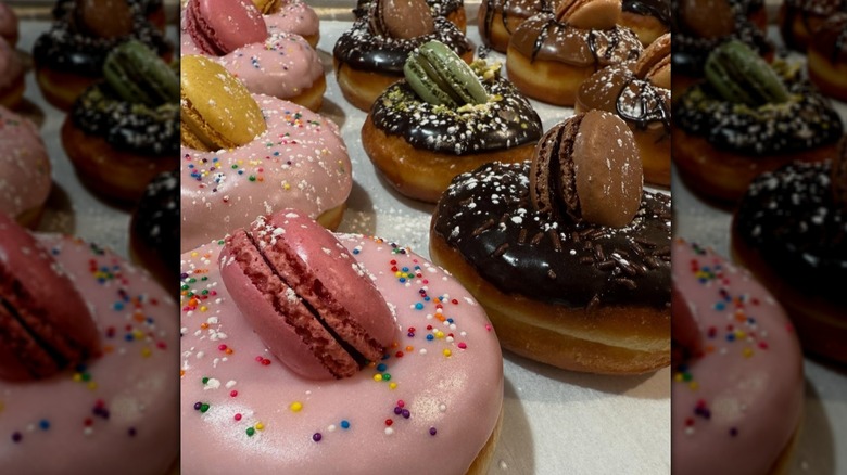 Pink and chocolate frosted raised donuts with macarons in the center from Enzo Benzo