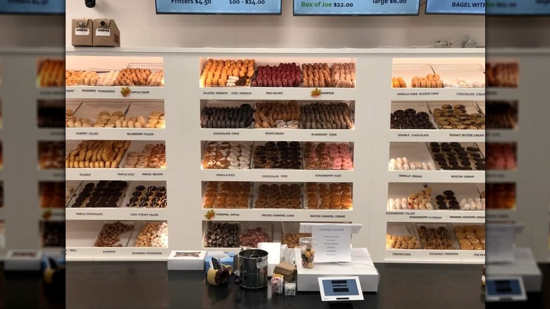 The main counter at Dough n Joe, with dozens of different donut options on shelves on the back wall